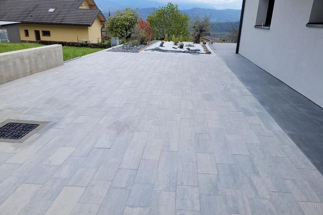 Grande allée dallée le long d’une maison contemporaine