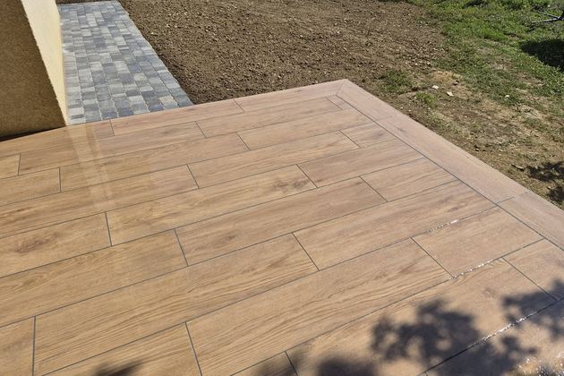 Terrasse en dallage effet bois bordée de pavés